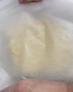 Una persona tiene un pezzo di carta oleata sopra un pezzo di pasta.