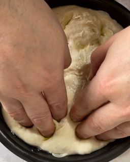 Una persona sta impastando l'impasto con le mani in una padella.