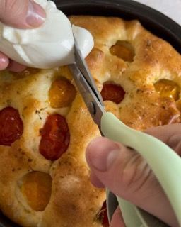 Una persona sta tagliando un pezzo di pizza con le forbici