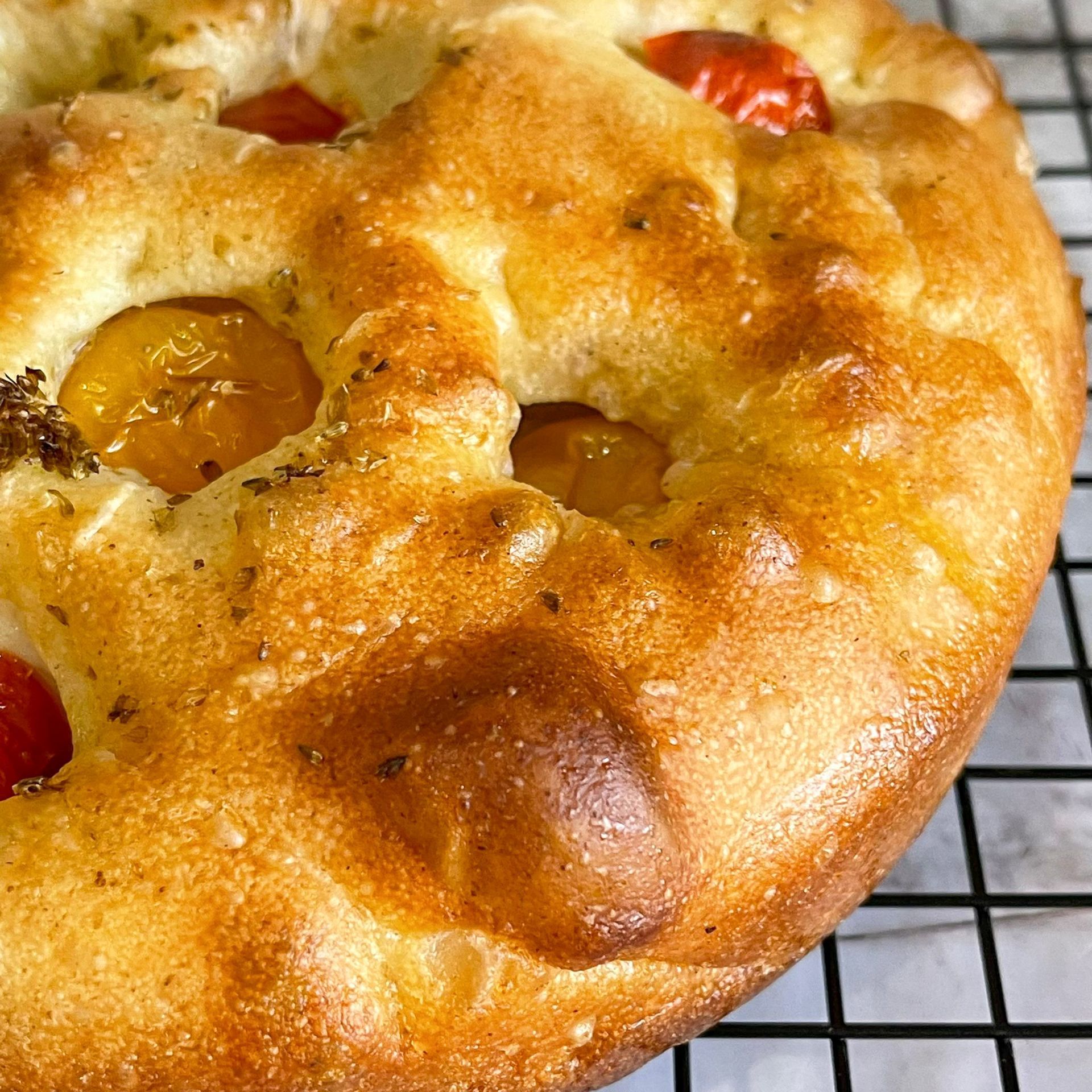 Primo piano di una pagnotta con pomodori su una griglia di raffreddamento.
