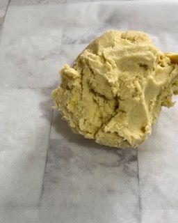 Una palla di pasta è appoggiata su un pezzo di carta oleata.