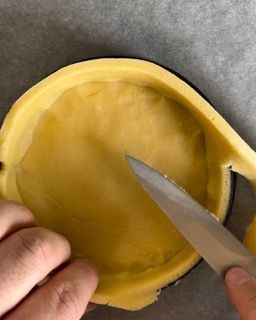 Una persona sta tagliando un pezzo di pasta con le forbici.