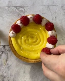 Una crostata con crema al limone e lamponi sopra