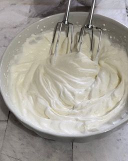 Una ciotola di panna montata con dentro un mixer