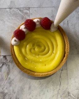 Una pasta sfoglia con glassa gialla e lamponi sopra