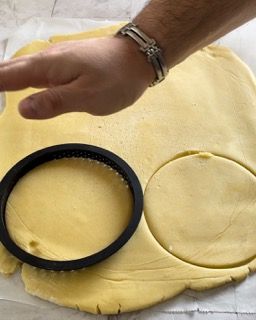 Una persona sta tagliando un cerchio da un pezzo di pasta