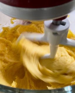 Un mixer sta mescolando un liquido giallo in una ciotola di vetro.