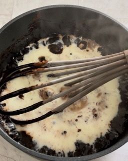 Una frusta sta mescolando una salsa in una padella