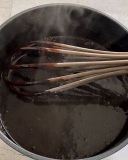 Una ciotola di liquido marrone con una frusta dentro