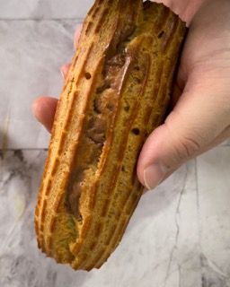 Una persona tiene in mano un dolce ripieno di cioccolato.