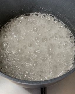 Una pentola di acqua bollente da cui escono delle bollicine.