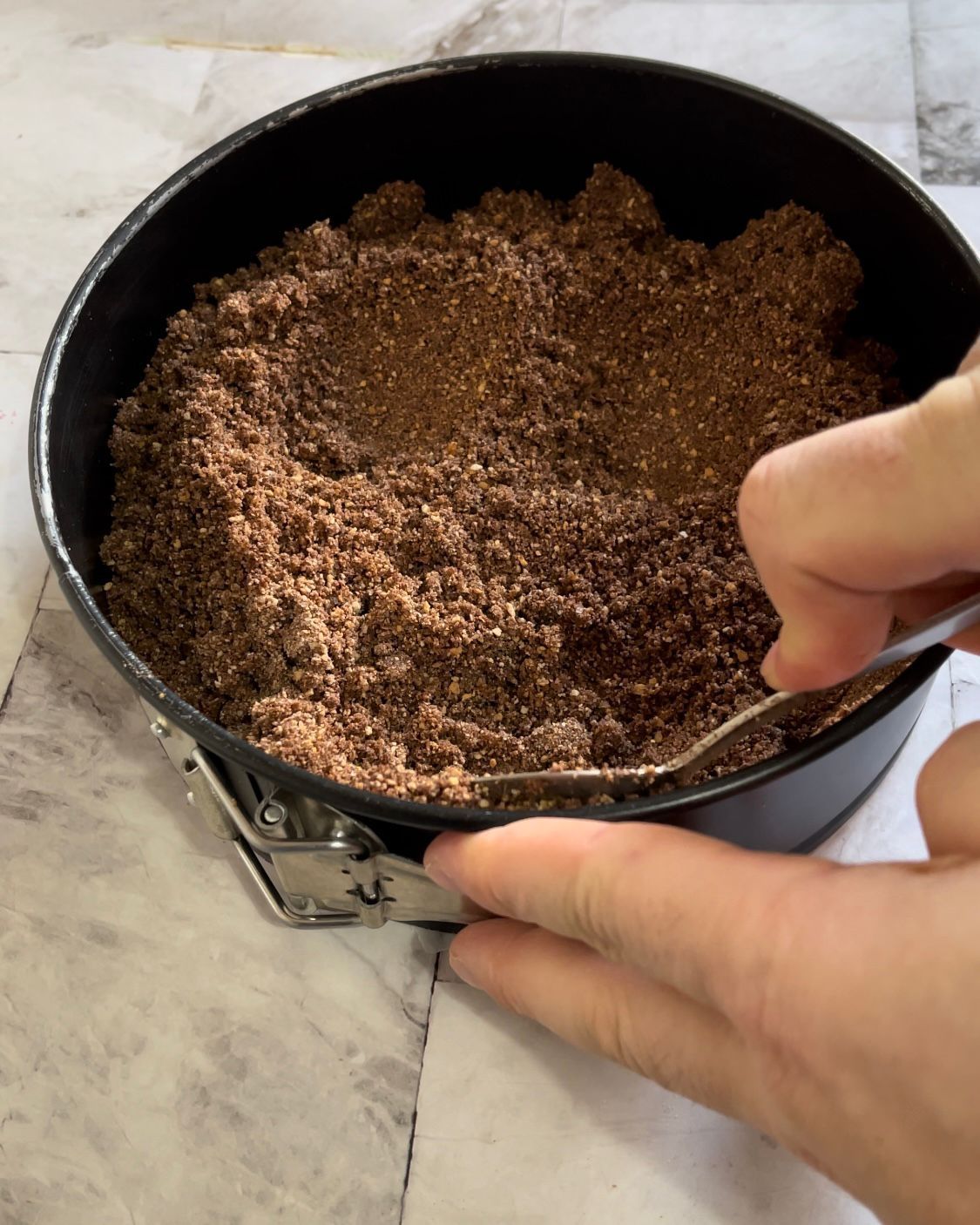 Una persona sta preparando una torta in una teglia con una forchetta.