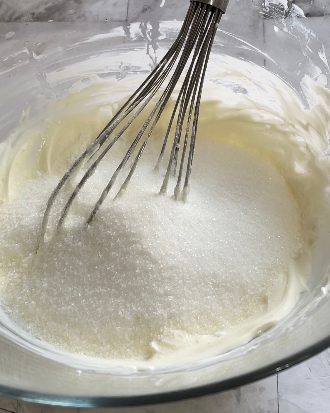 Una frusta è in una ciotola di zucchero e panna montata