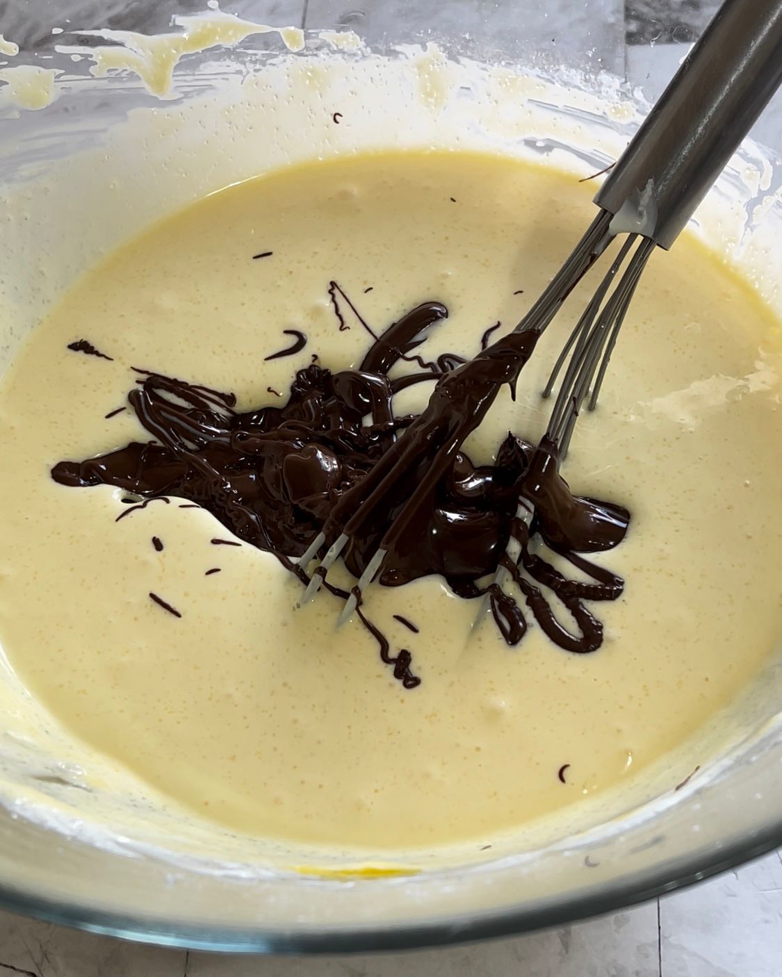 Una ciotola di pastella con gocce di cioccolato e una frusta dentro