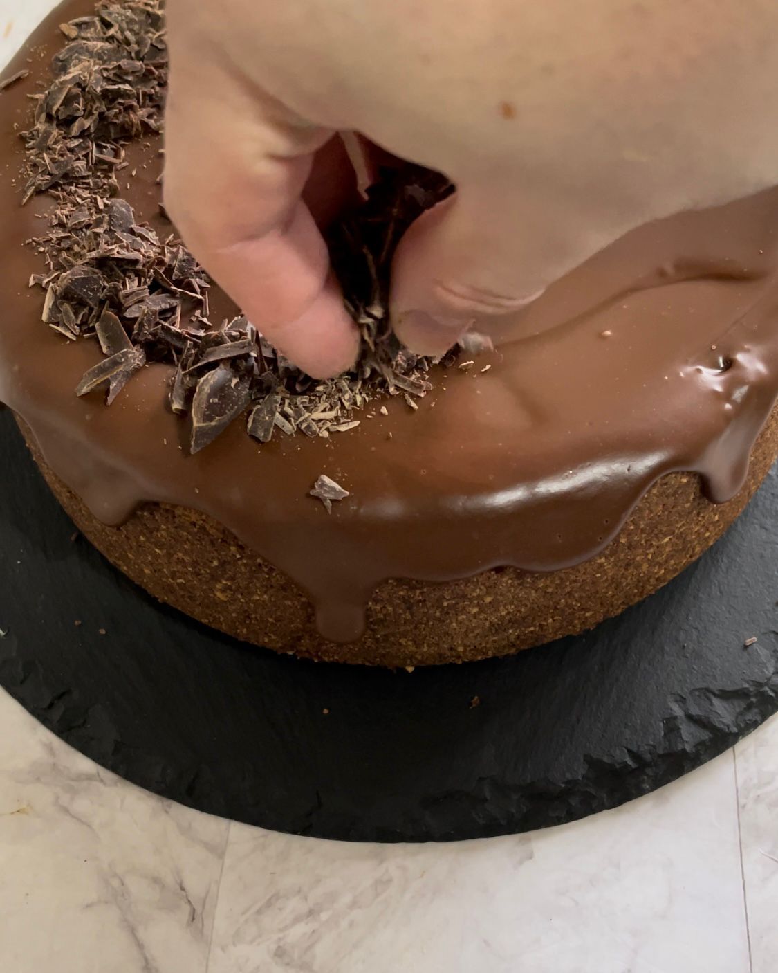 Un primo piano della mano di una persona su una torta al cioccolato