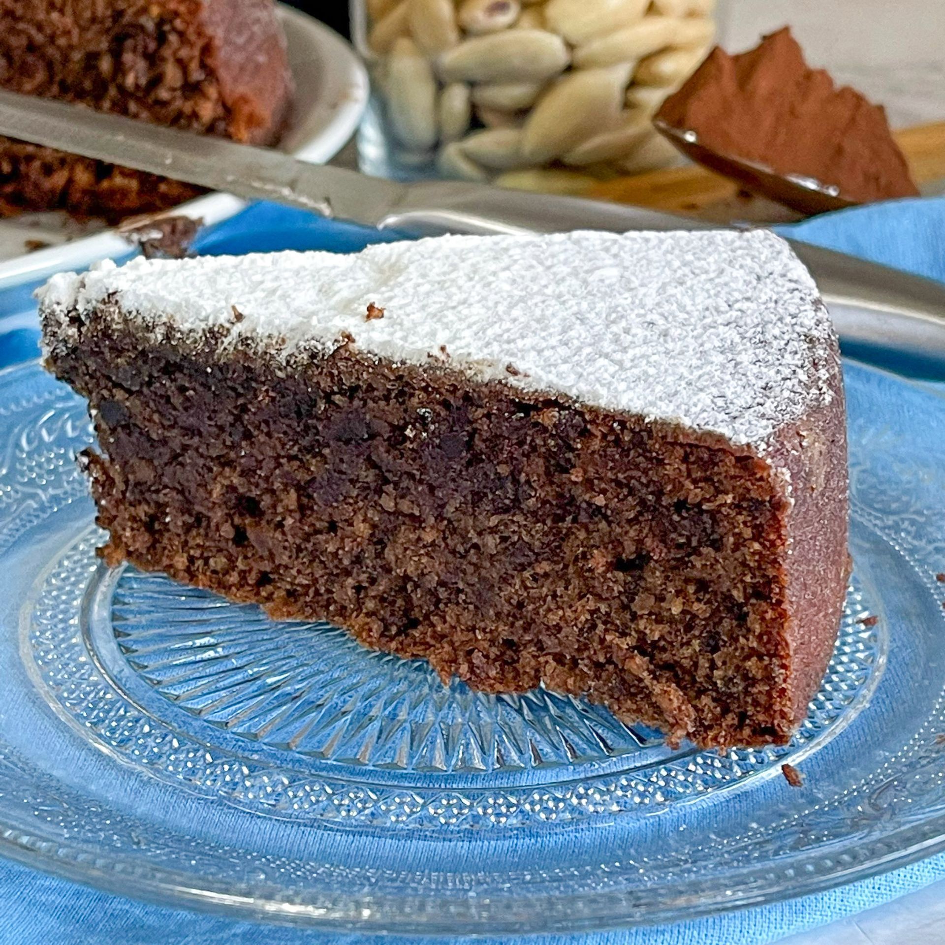 Una fetta di torta al cioccolato con zucchero a velo su un piatto di vetro