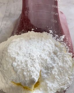 Burro morbido e zucchero a velo in una ciotola, lavorati con una spatola.