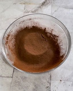 Una ciotola di vetro piena di polvere marrone su un tavolo