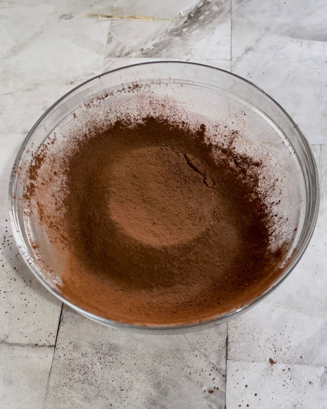 Una ciotola di vetro piena di cioccolato in polvere su un tavolo.