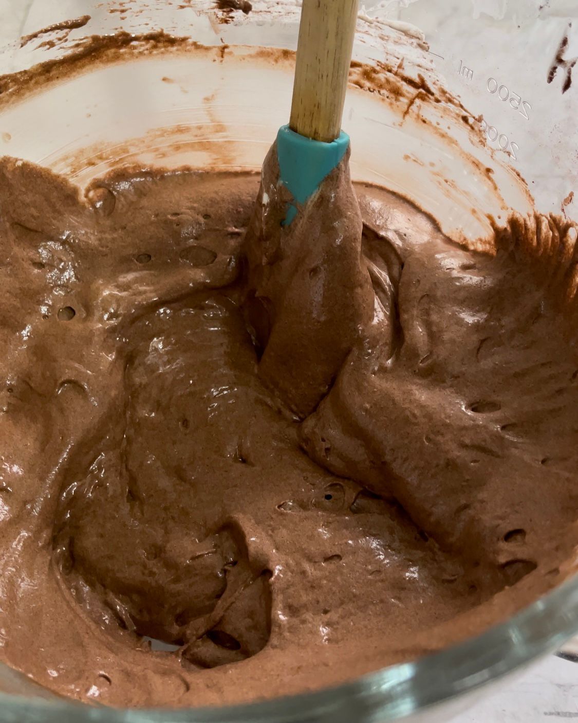 Una ciotola di glassa al cioccolato con una spatola dentro