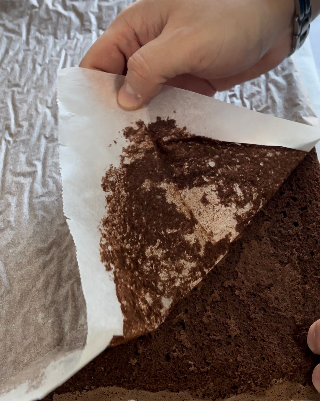 Una persona tiene in mano un pezzo di carta sopra una fetta di torta al cioccolato.