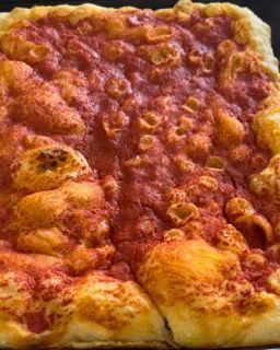 Una pizza con salsa di pomodoro e formaggio è appoggiata su un tavolo.