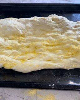 Un pezzo di pasta è appoggiato su una padella nera.