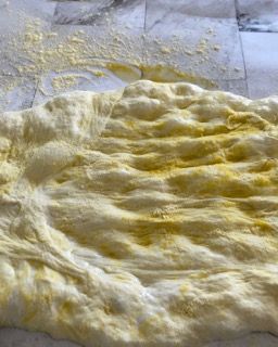 Un impasto per pizza è appoggiato su un pavimento piastrellato.