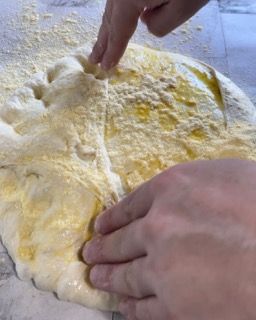 Una persona sta spalmando dell'olio sull'impasto della pizza.