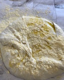 Un pezzo di pasta è appoggiato su un tavolo ricoperto di farina.