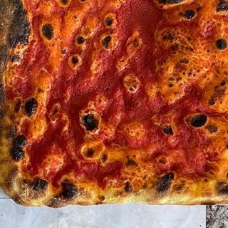 Un primo piano di una pizza con salsa di pomodoro su un tavolo.
