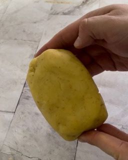 Una persona tiene in mano un pezzo di pasta gialla