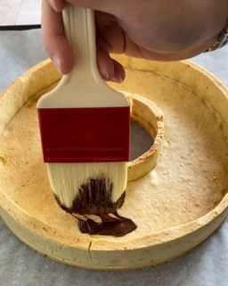 Una persona sta usando un pennello per spalmare il cioccolato su una torta