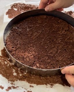 Una persona sta tagliando una torta al cioccolato in una teglia.