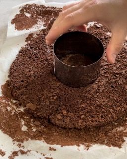 Una persona sta tagliando una torta al cioccolato con uno stampino rotondo.