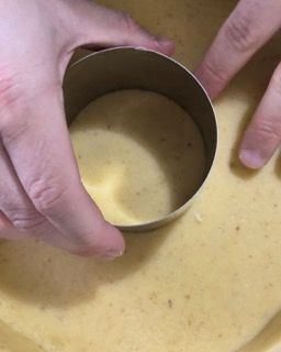 Una persona tiene in mano un anello di metallo sopra una ciotola di zuppa.