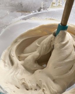 Una ciotola di glassa con un cucchiaio di legno dentro.