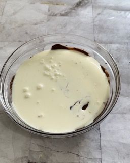 Una ciotola di vetro piena di besciamella e cioccolato su un tavolo.