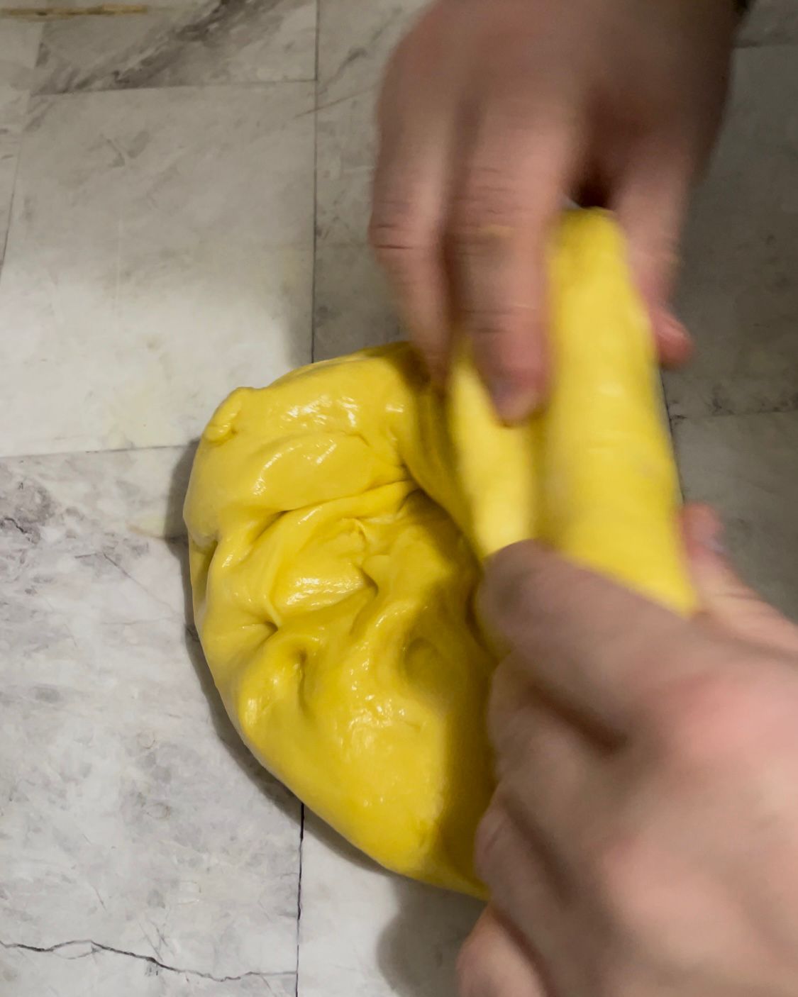 Una persona tiene in mano un pezzo di pasta gialla.