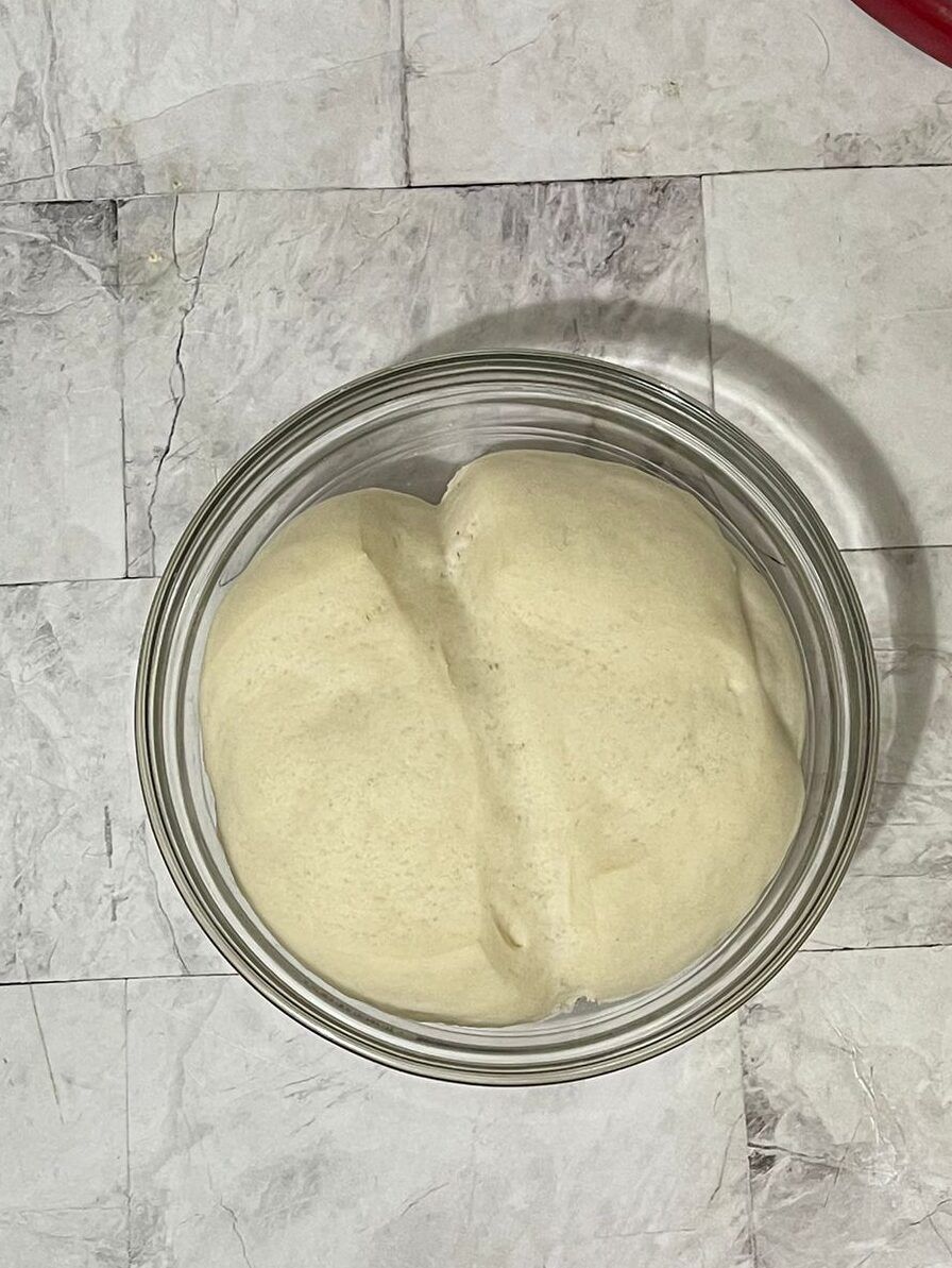 Una ciotola di vetro piena di una sostanza bianca è appoggiata su un tavolo.