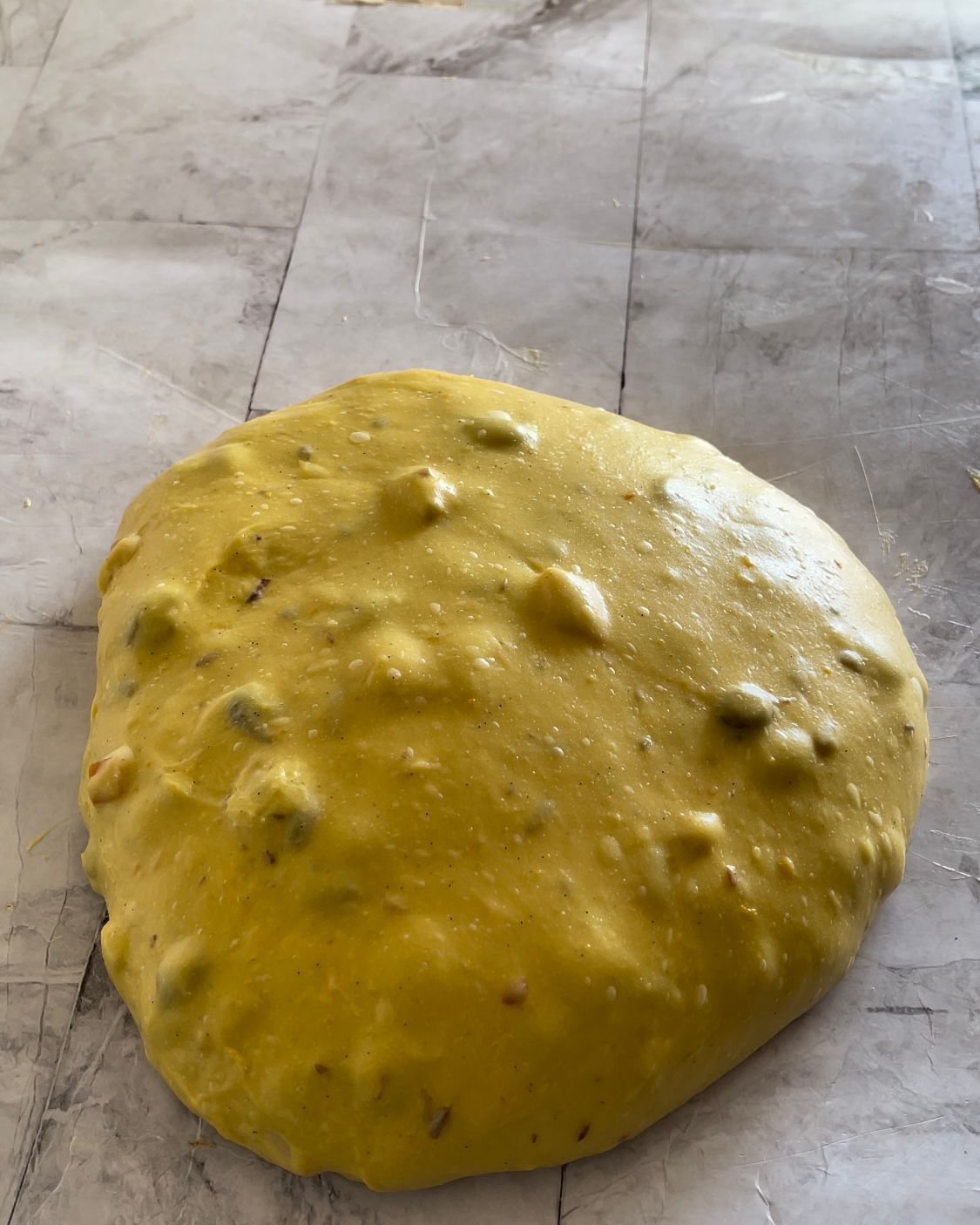 Una grande palla gialla di pasta è appoggiata su un tavolo.