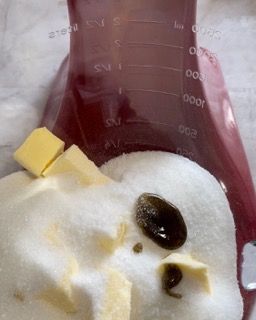 Una tazza graduata viola piena di zucchero e burro