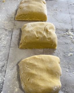 Tre pezzi di pasta sono appoggiati su un tavolo.