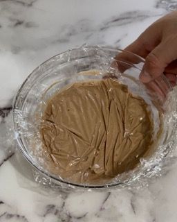 Una persona tiene in mano una ciotola di cibo avvolta nella pellicola trasparente.