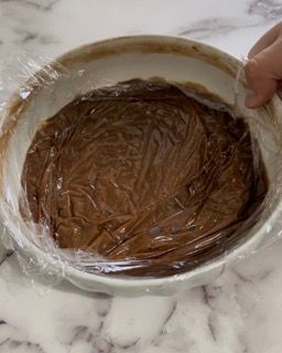 Una persona sta avvolgendo una ciotola di salsa al cioccolato nella pellicola trasparente.