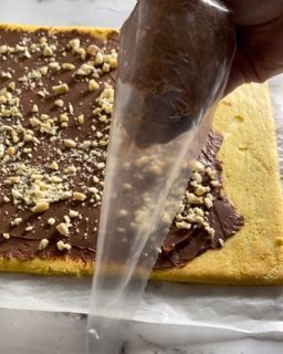 Una persona sta glassando una torta con cioccolato e noci
