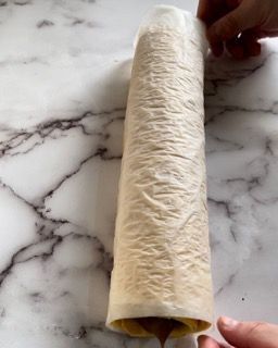 Una persona sta arrotolando una tortilla su un tavolo di marmo.