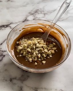 Una ciotola di salsa al cioccolato con noci e un cucchiaio dentro