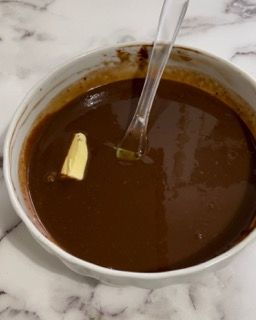 Una ciotola di zuppa al cioccolato con un pezzetto di burro sopra.