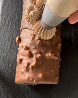 Una persona sta glassando una torta al cioccolato con una sac à poche.
